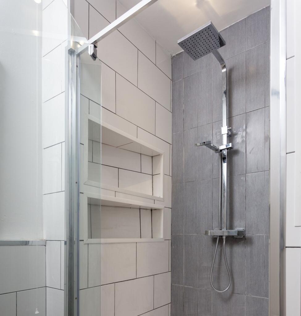 A modern bathroom shower area featuring sleek g...