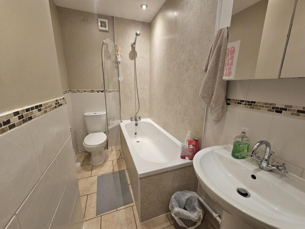 Bright, modern bathroom with a bathtub and over...