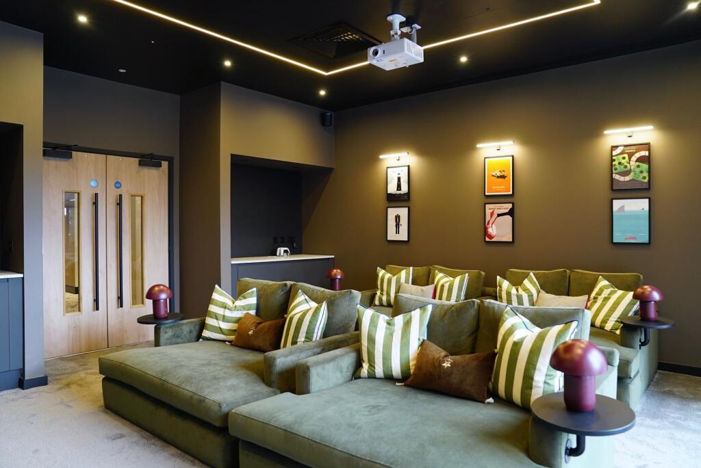 A stylish cinema room featuring plush green sof...