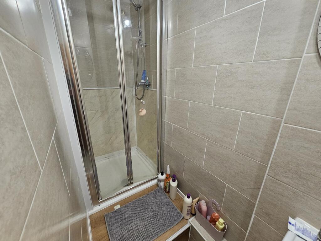 Modern tiled bathroom with a walk-in shower, gl...