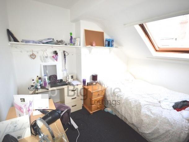 A cozy single bedroom featuring a sloped ceilin...