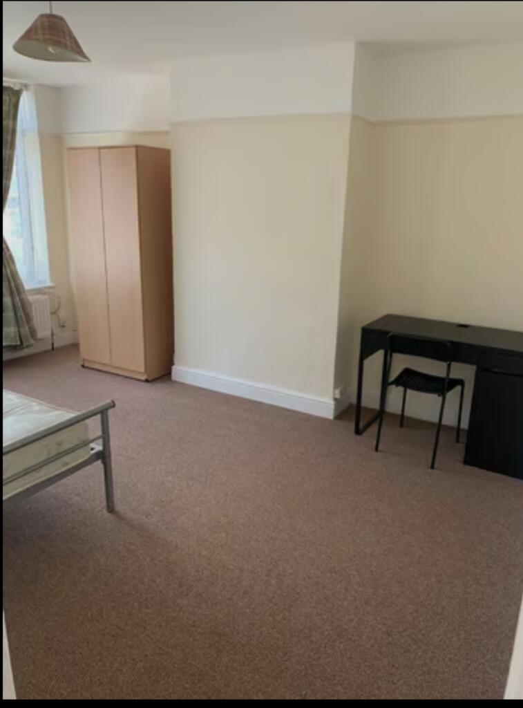 A spacious and tidy double bedroom featuring a ...