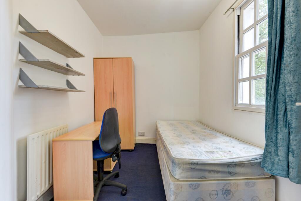 A simple, bright single bedroom featuring a stu...