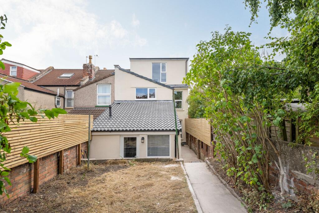 Rear garden with paved pathway leading to a mod...
