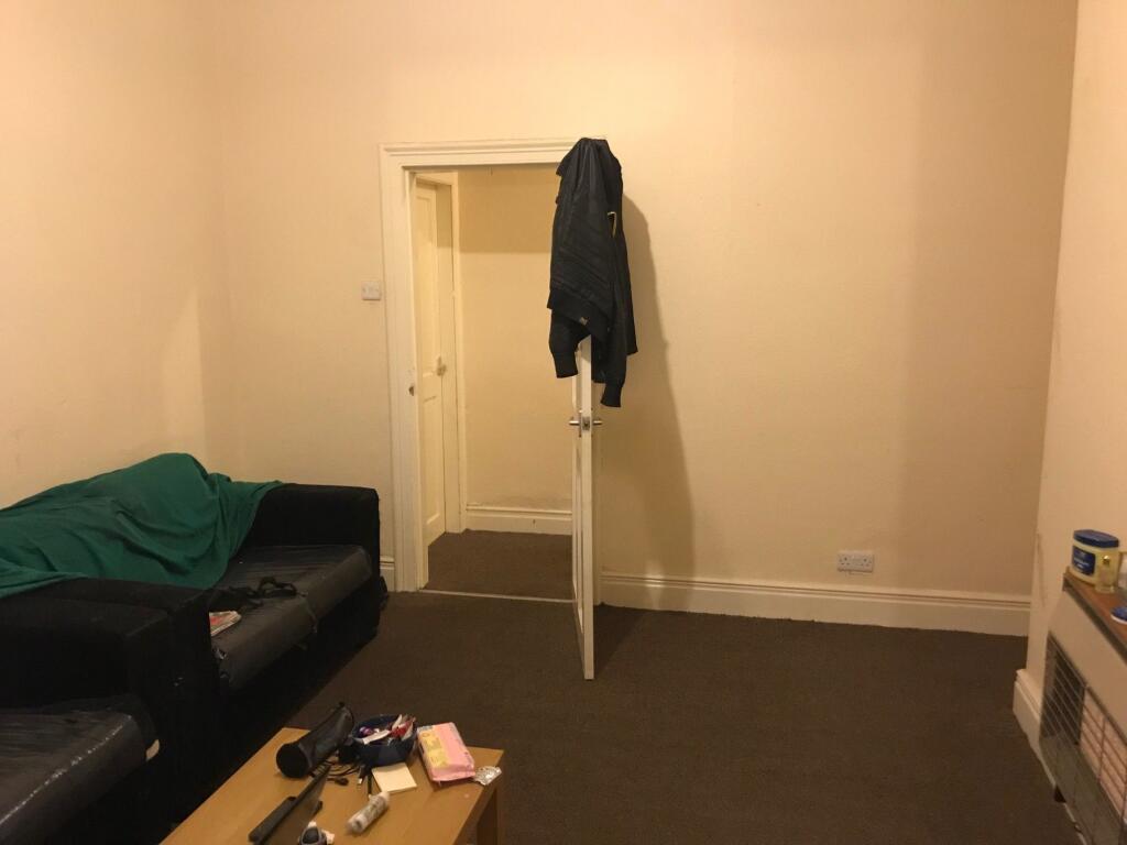 A modest living room featuring a black sofa wit...