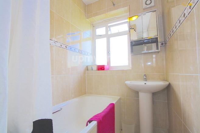 A clean and bright bathroom featuring a bathtub...