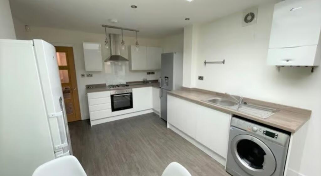 Modern kitchen featuring white cabinetry, a sta...