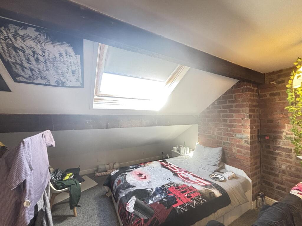 A cozy bedroom with a skylight window allowing ...