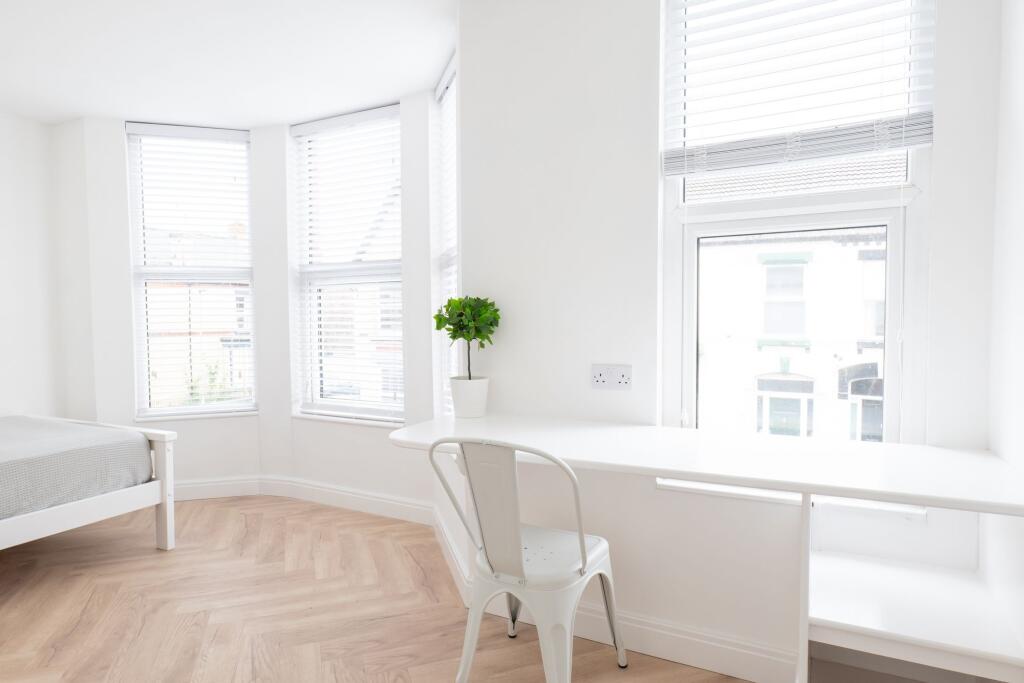 Bright and airy bedroom with large windows, whi...