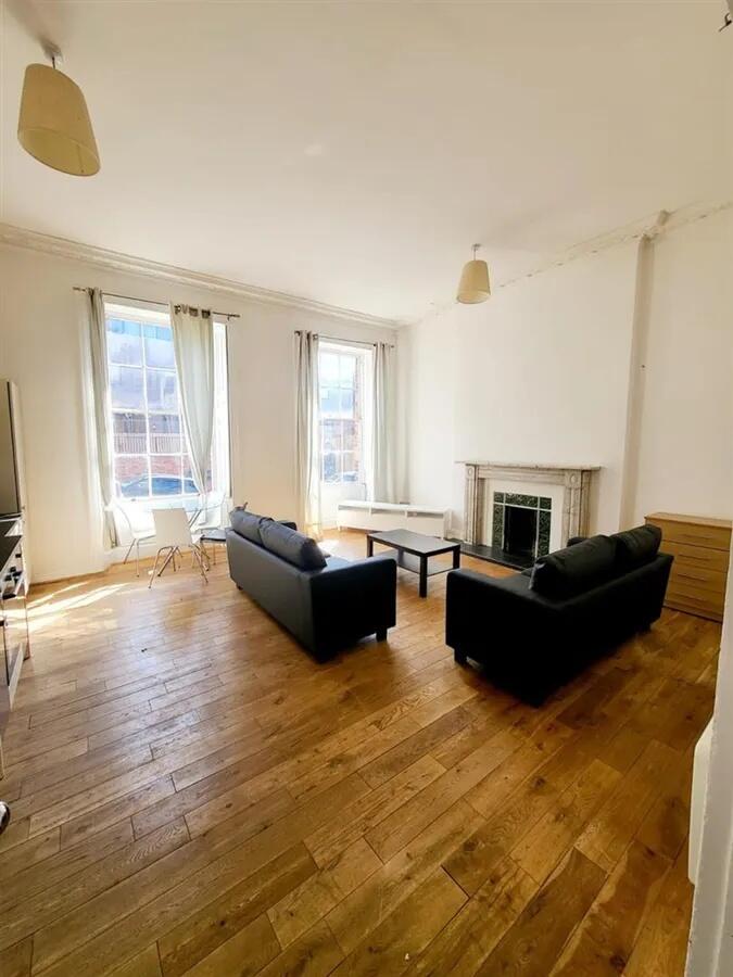 A spacious, bright living room with large windo...