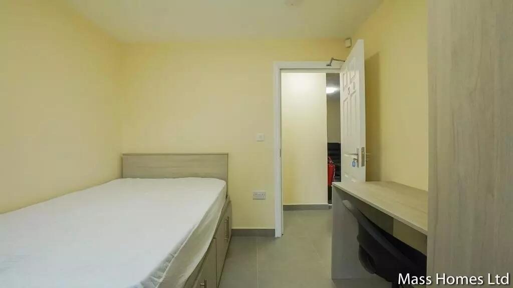 A neat and tidy single bedroom featuring a comf...