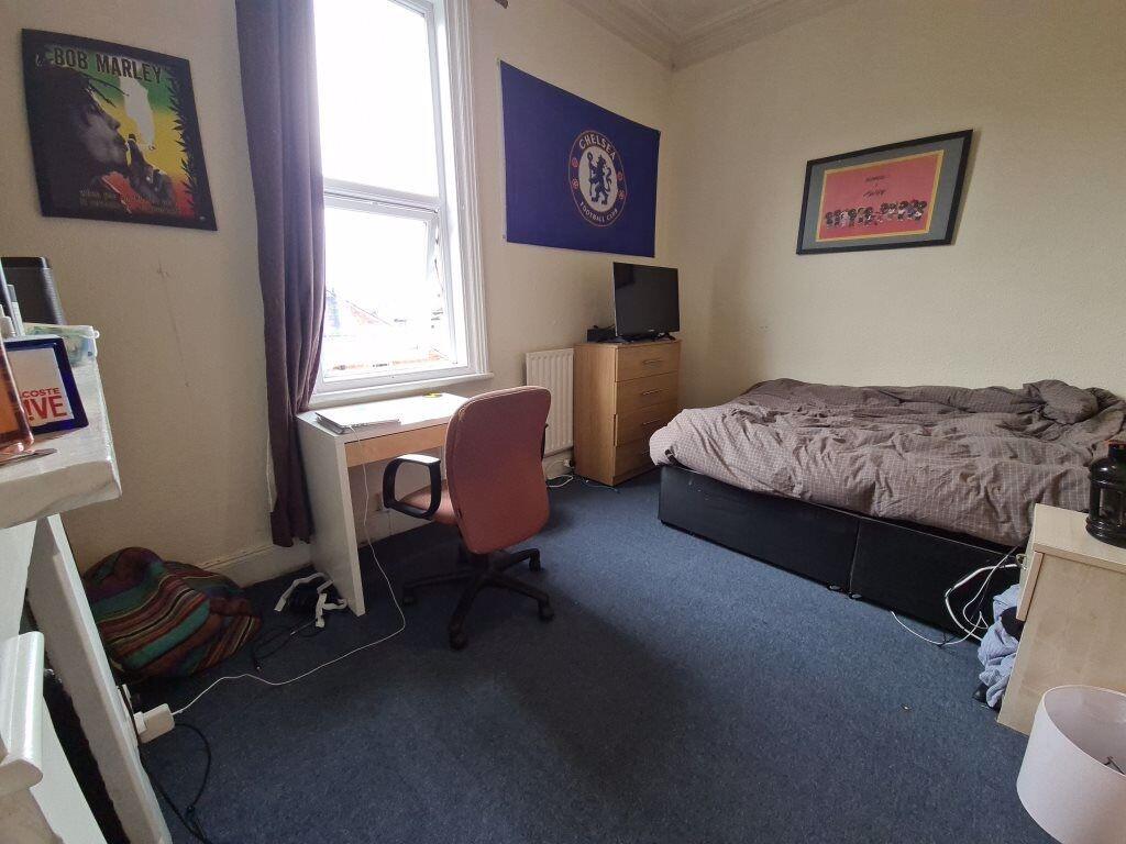 A cozy single bedroom featuring a bed, a window...