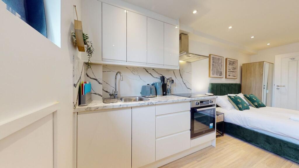 A modern and tidy studio bedroom featuring a co...