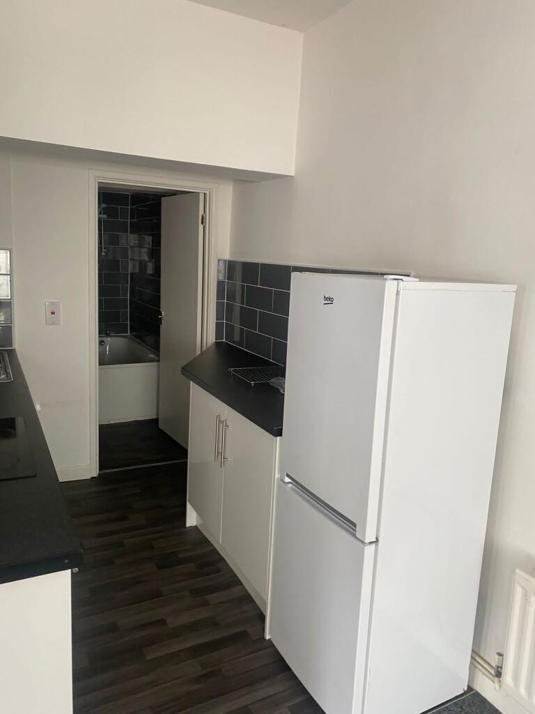Modern kitchen with white cabinetry, a black co...