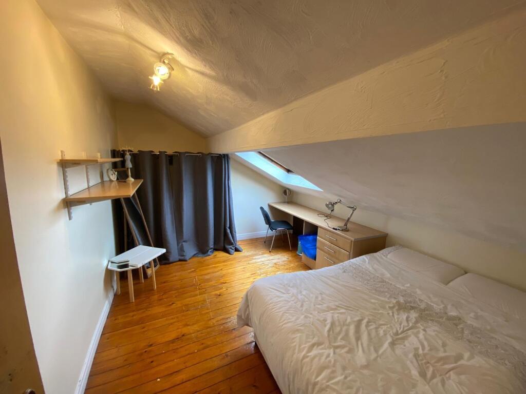 Cozy attic bedroom with a sloped ceiling, woode...