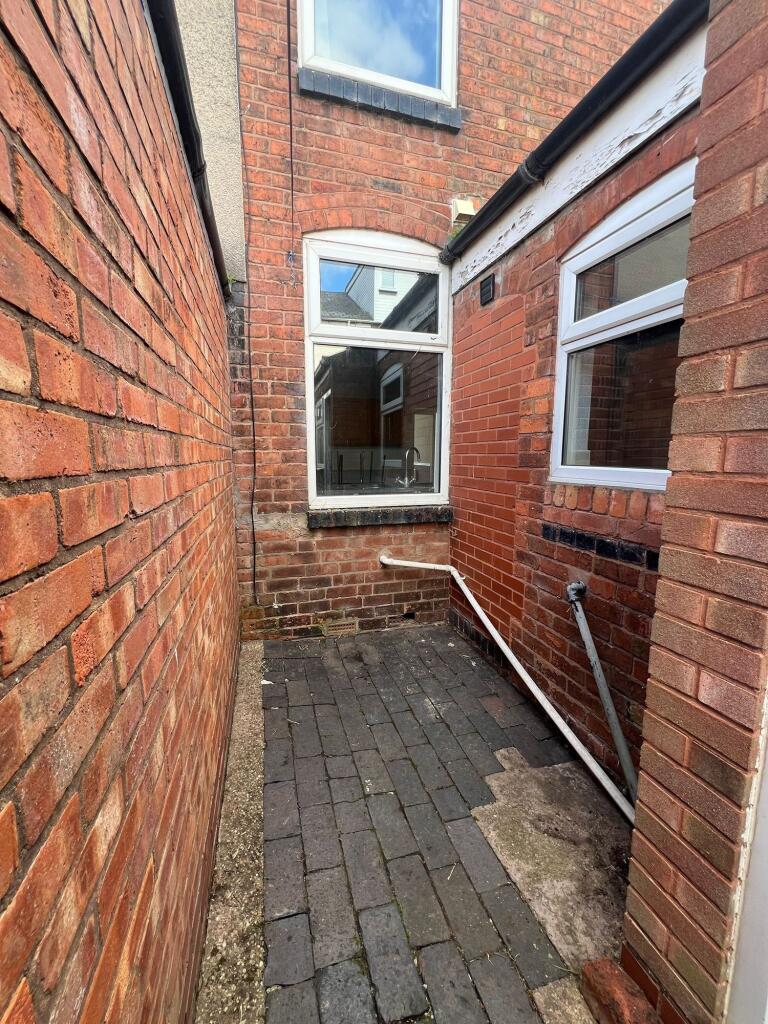 A narrow, enclosed outdoor space with brick wal...