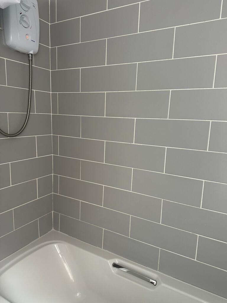 Modern bathroom featuring sleek grey tiled wall...