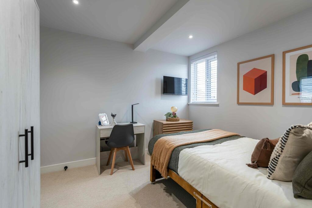 A spacious, well-lit bedroom featuring a large ...