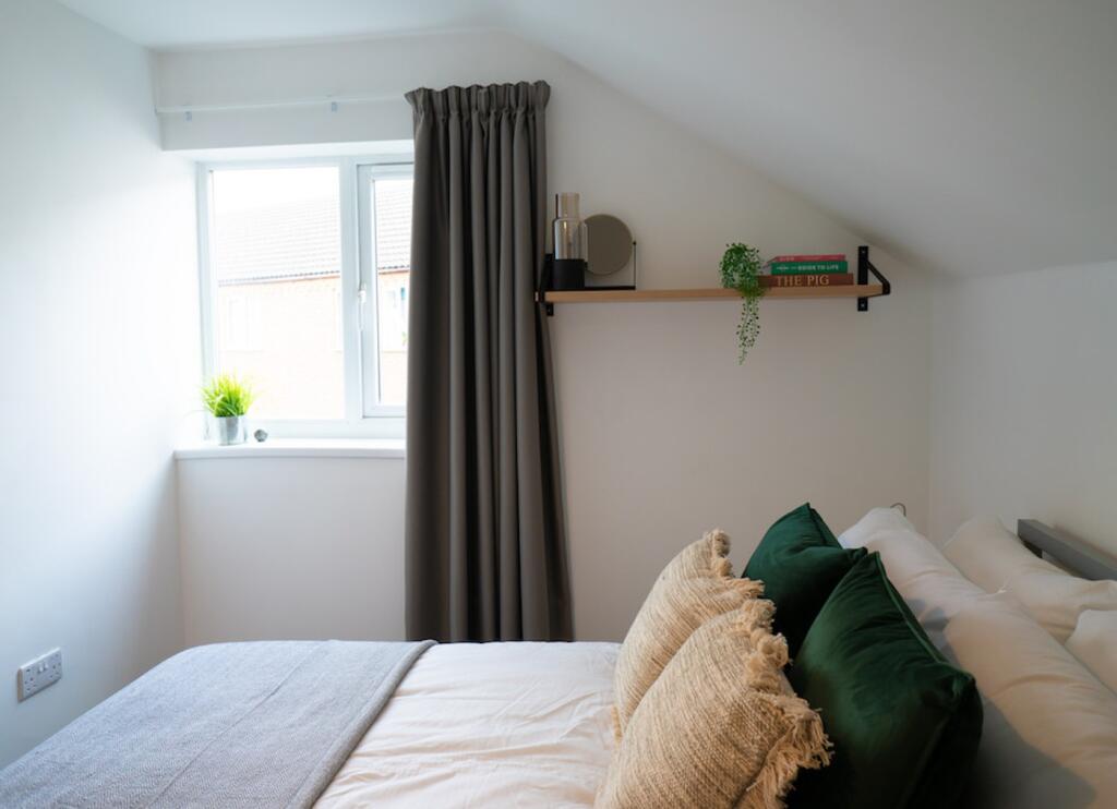 A bright and inviting double bedroom with styli...