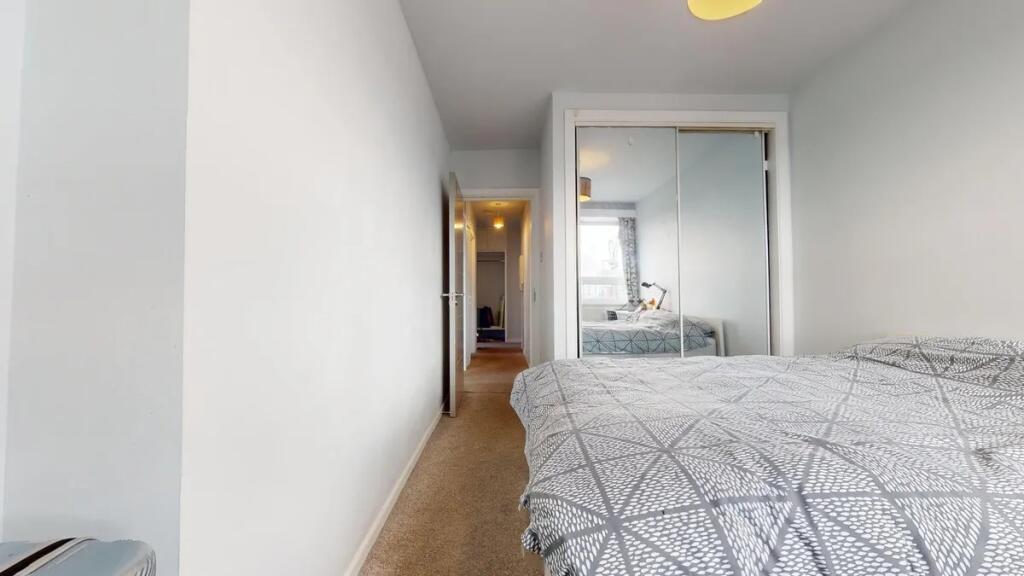 A bright double bedroom featuring a neatly made...