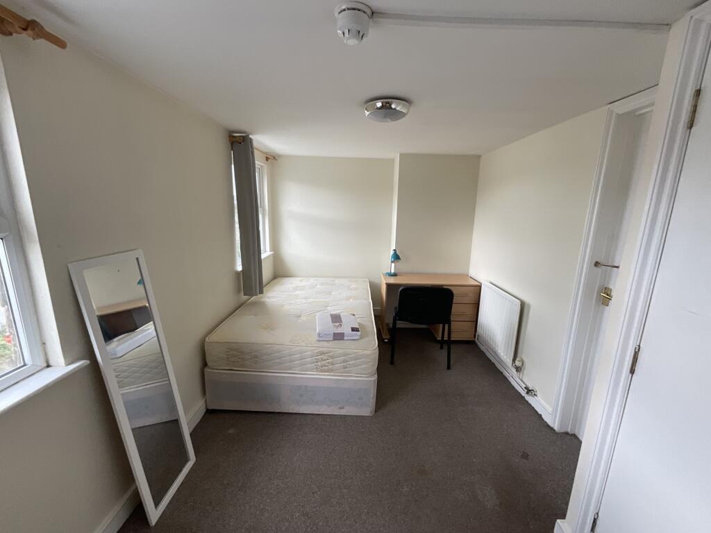 A simple, bright single bedroom featuring a bed...
