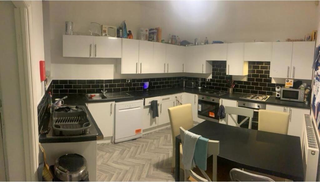 Modern kitchen area featuring white cabinets, a...