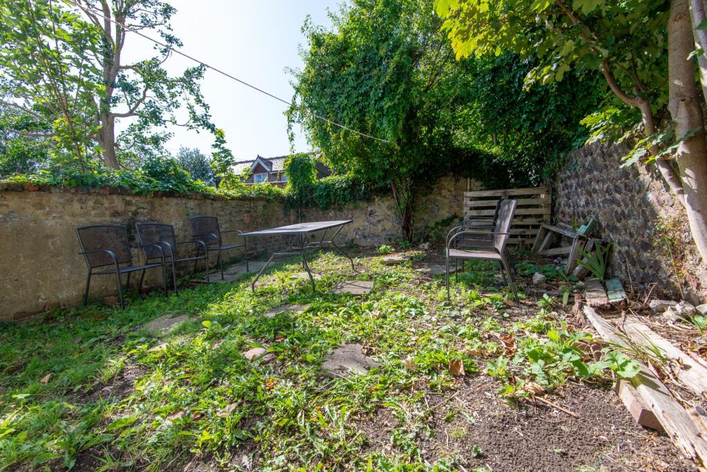 A charming garden with mature trees and stone w...