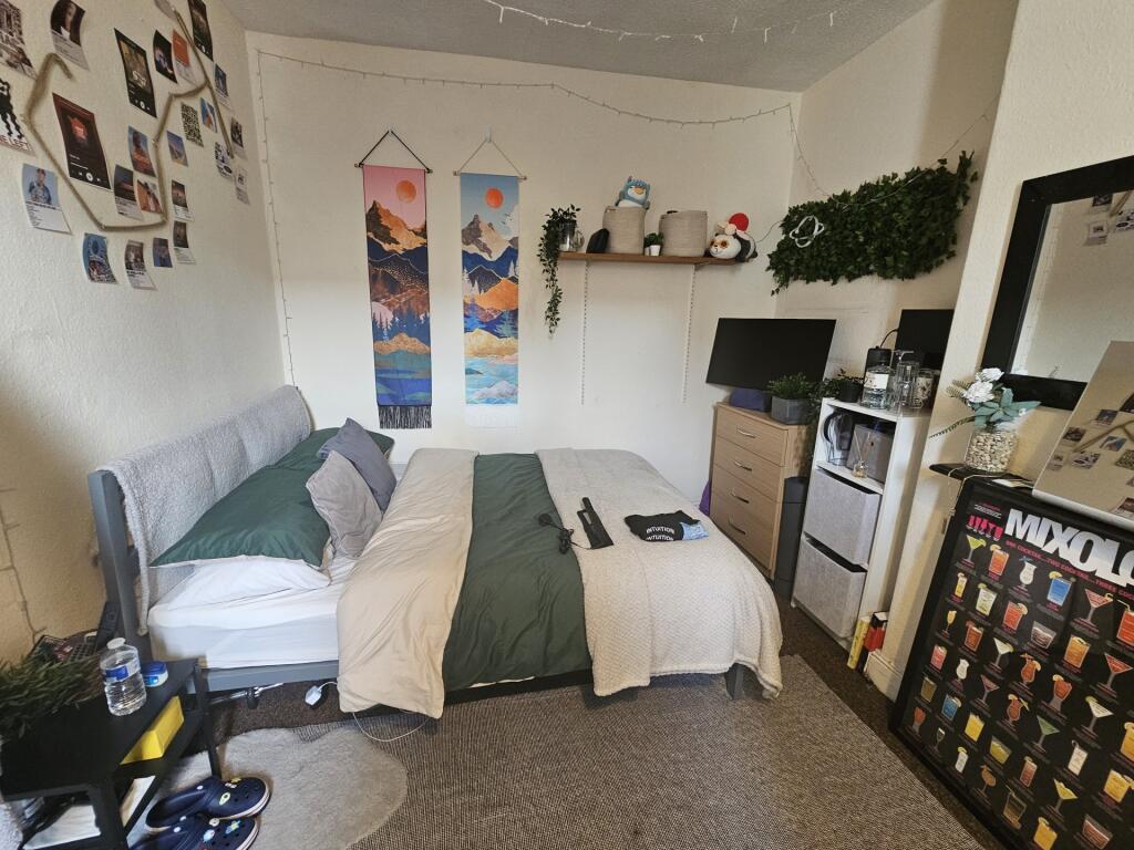 A cozy, well-organized single bedroom featuring...