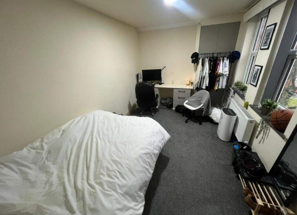 A cozy student bedroom featuring a simple bed s...