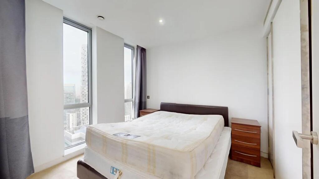 Bright double bedroom featuring two large windo...