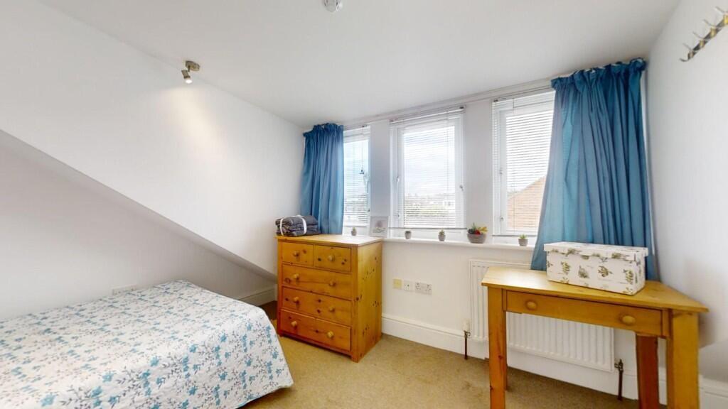 A bright and cozy single bedroom featuring a co...