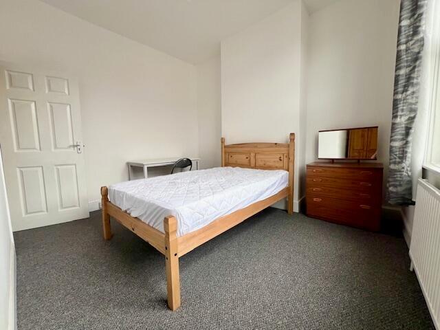 Bright double bedroom featuring a wooden bed fr...