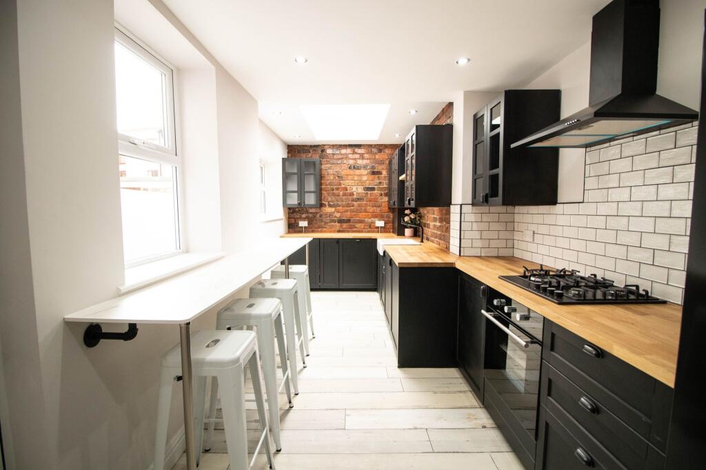 Modern kitchen with black cabinetry, wooden cou...