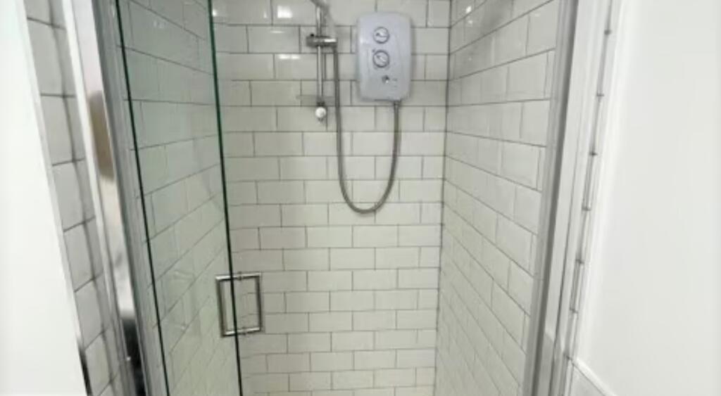 Modern, clean shower area featuring sleek white...
