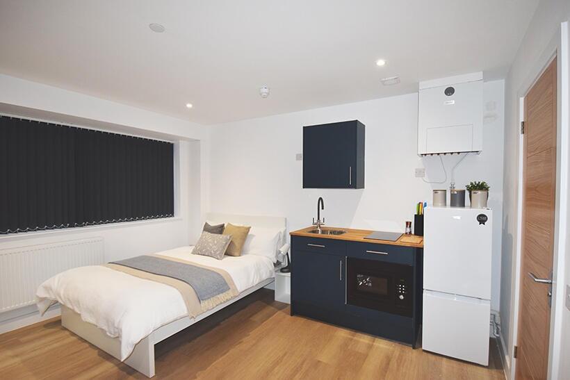A modern and tidy studio bedroom featuring a co...
