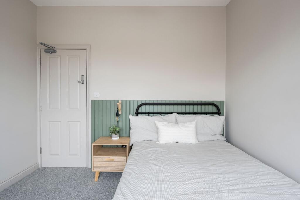 Bright, tidy bedroom with a metal-framed double...