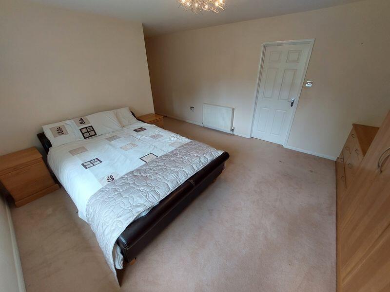 A spacious and tidy master bedroom featuring a ...