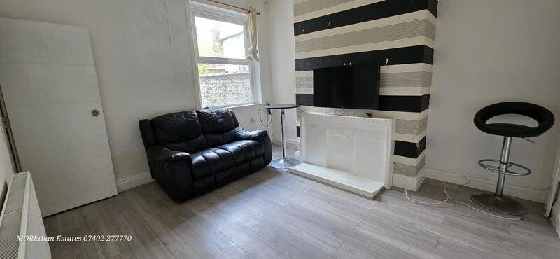 Cozy living room featuring a sleek black leathe...