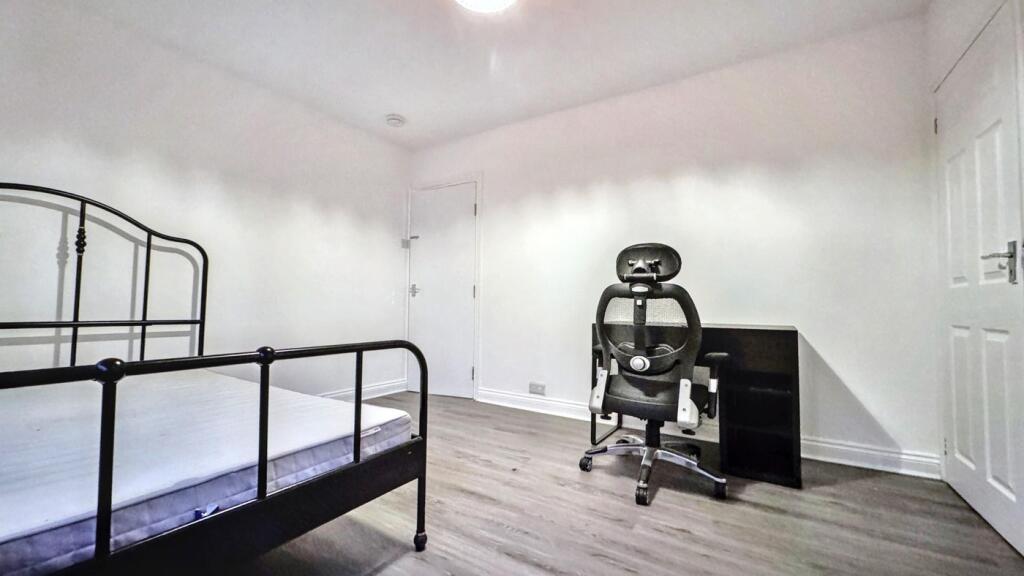 A spacious double bedroom with a modern desk an...