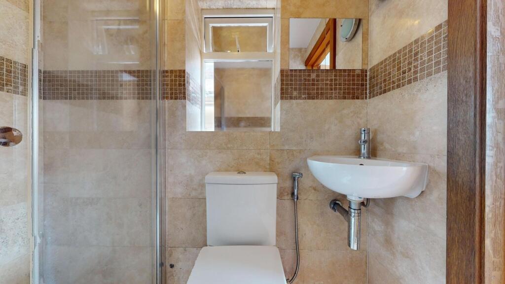 A modern, compact bathroom featuring a shower e...