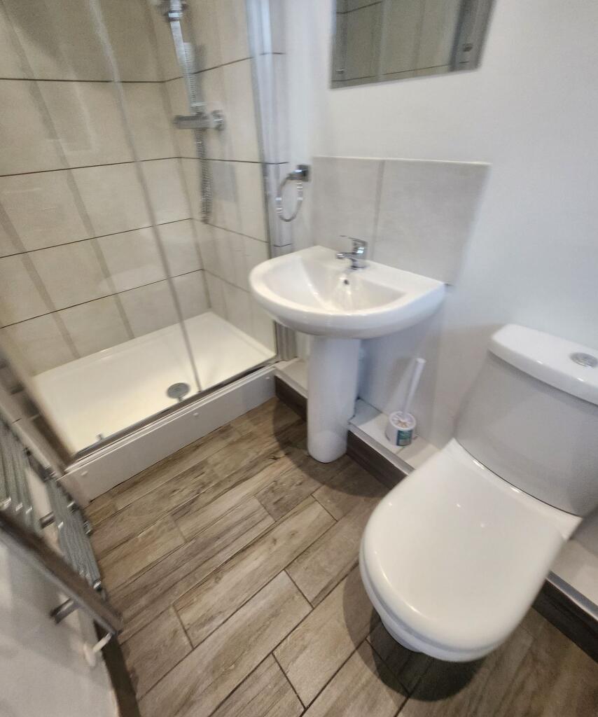 A compact bathroom featuring a shower enclosure...