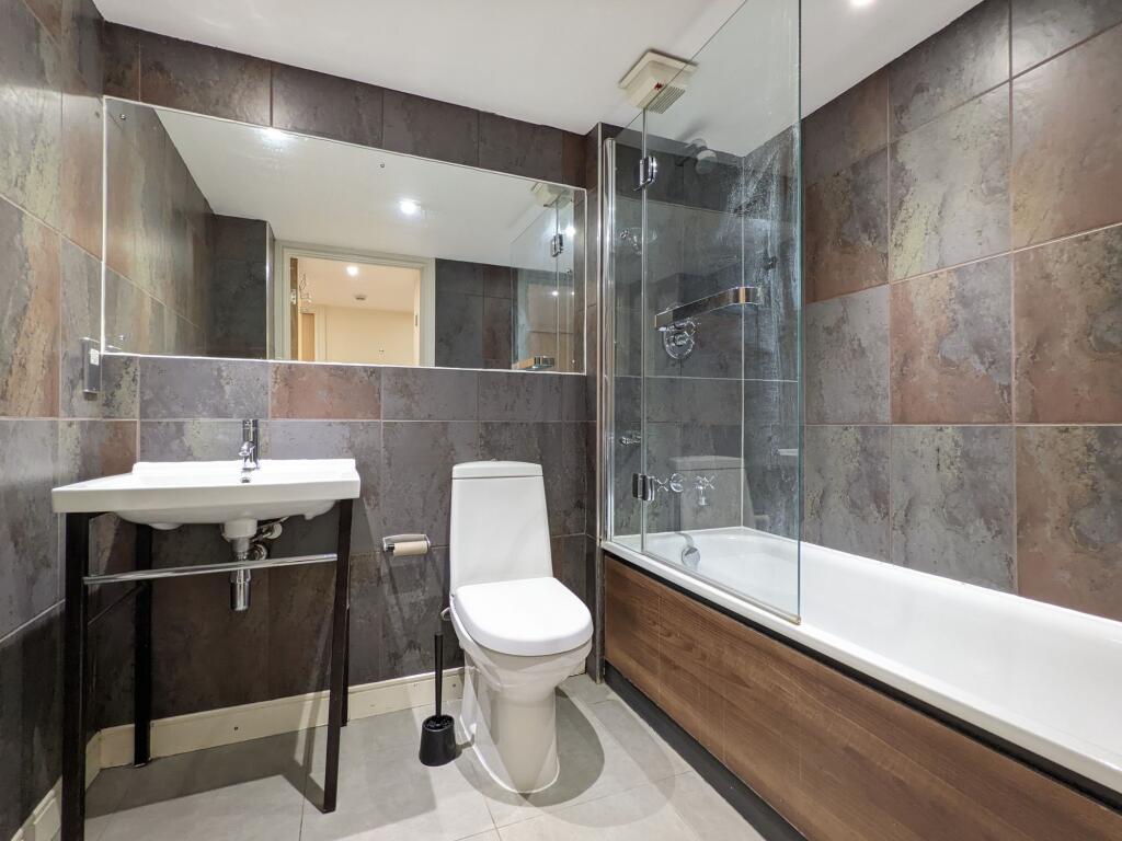Modern tiled bathroom with a full bathtub and g...