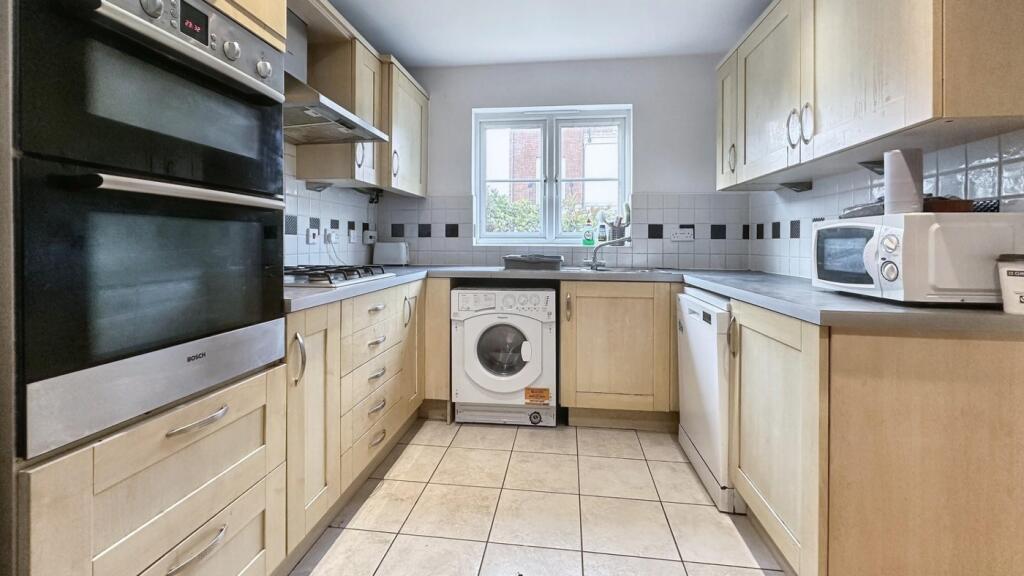 A tidy and well-lit kitchen with modern applian...