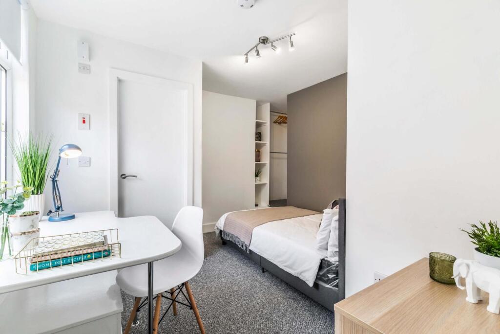 A bright and clean single bedroom featuring a c...