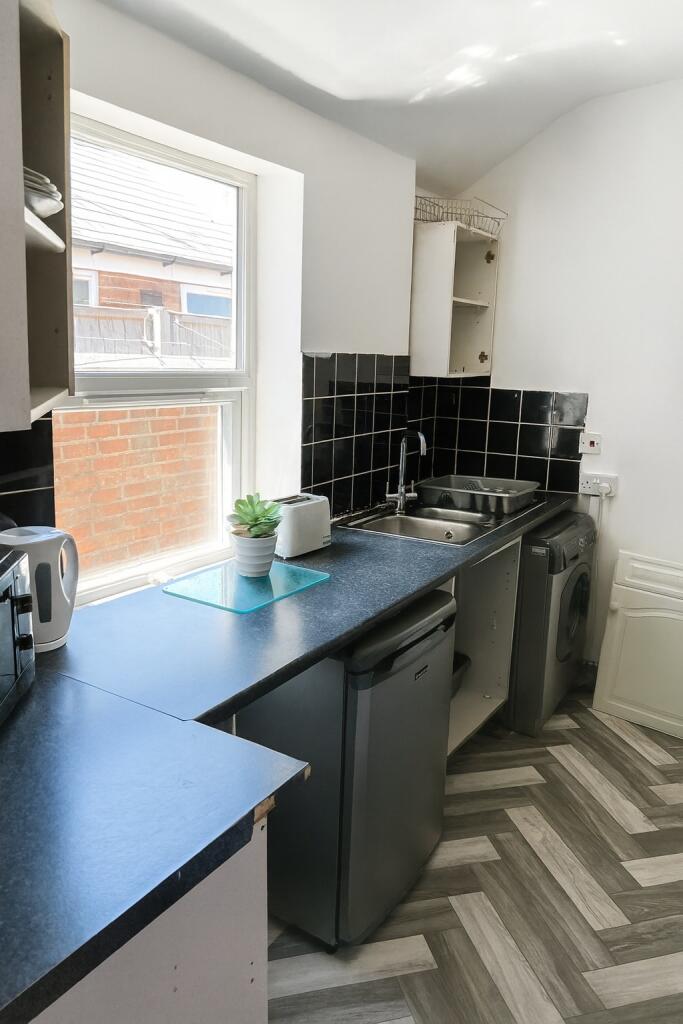 Bright compact kitchen with a large window, mod...