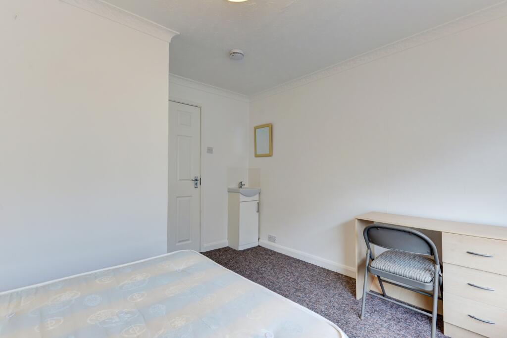 A bright and tidy single bedroom featuring a si...