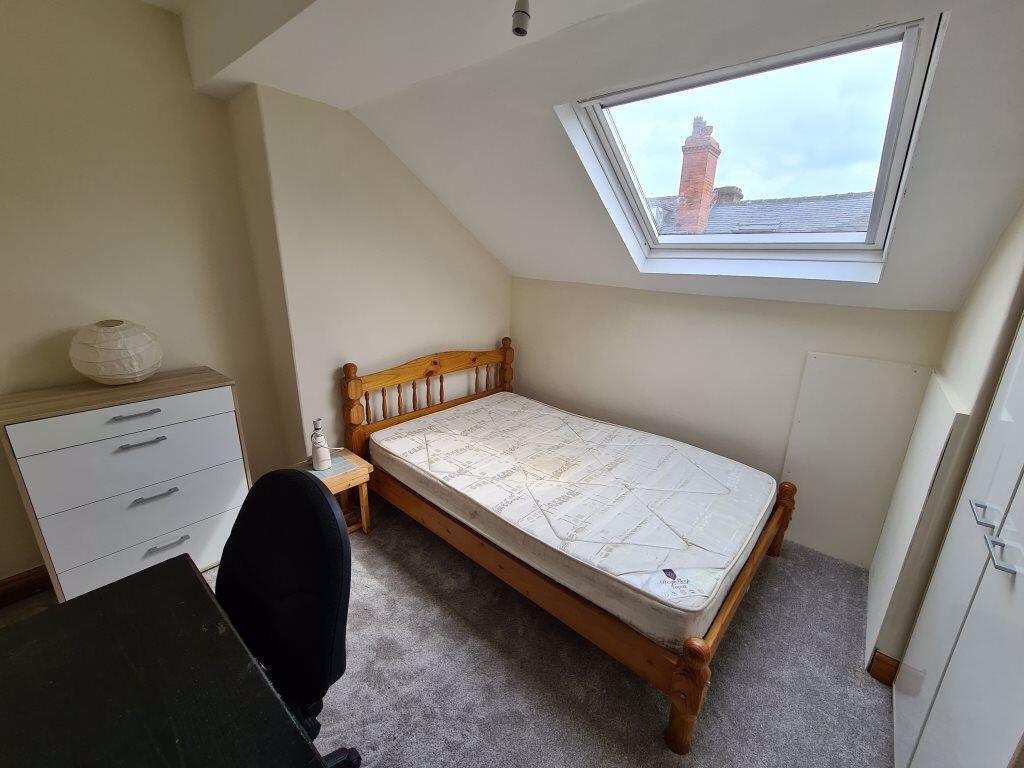 Bright and cozy single bedroom featuring a slop...