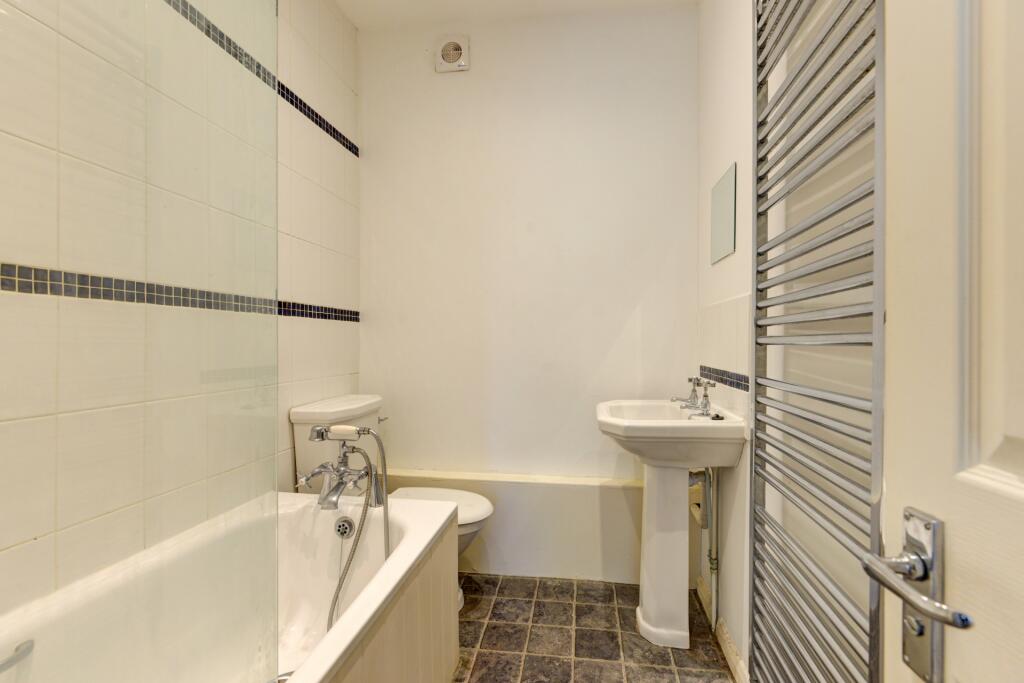 Bright and clean bathroom suite featuring a whi...