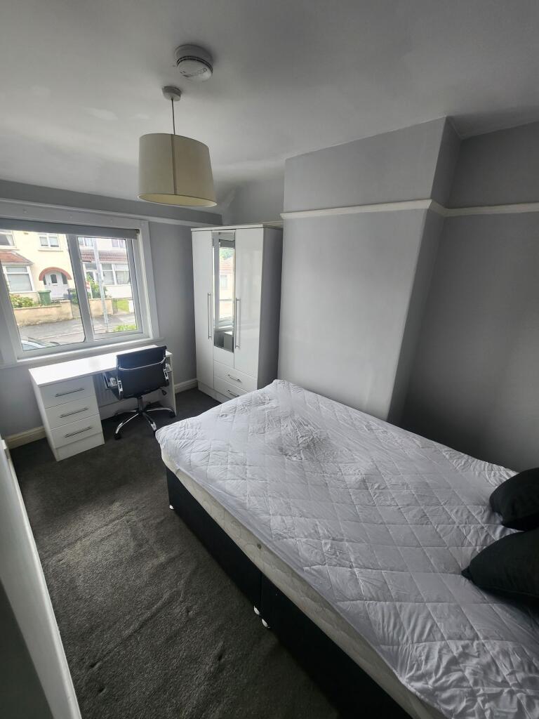 A bright double bedroom featuring a large windo...