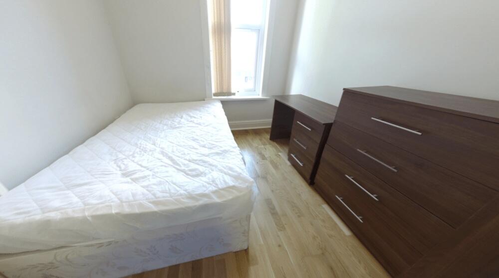A bright and tidy bedroom featuring a large bed...
